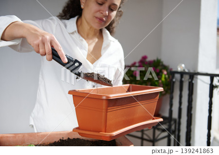 Woman Filling Planter With Soil On Balcony While Gardening With Trowel Woman Filling Planter With Soil On Balcony While Gardening With Trowel 139241863