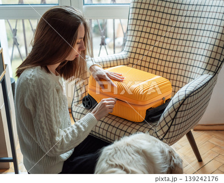 Woman packing yellow suitcase for travel journey at home Woman packing yellow suitcase for travel journey at home 139242176
