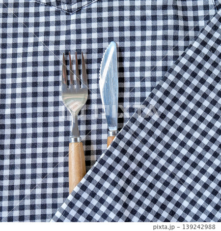 Knife and fork in folded napkin at background, top view. Knife and fork in folded napkin at background, top view. 139242988