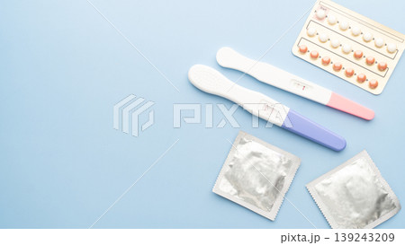 Pregnancy test with birth control pills and condoms on blue background. Contraception, family planning, sexual and reproductive health concept. 139243209