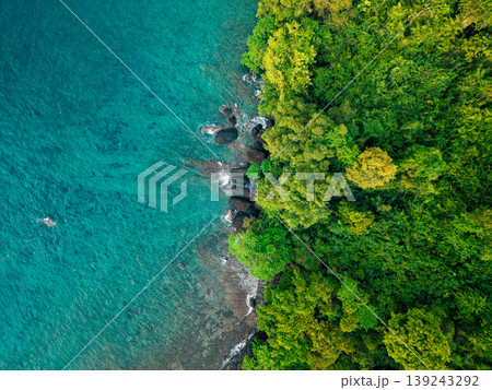 Aerial top-down view of turquoise ocean waves crashing on a rocky shoreline. Aerial top-down view of turquoise ocean waves crashing on a rocky shoreline. 139243292