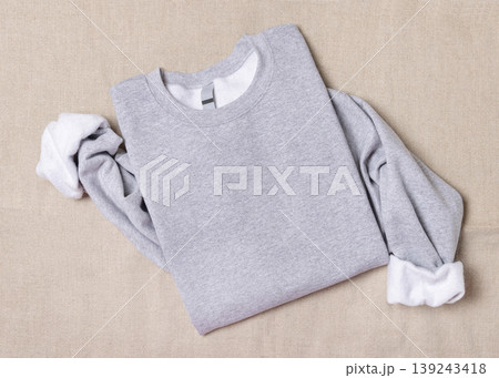 Blank sport grey oversized sweatshirt mockup on fair-haired young woman sitting on sofa, front view 139243418