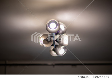 Modern ceiling chandelier with illuminated glass spheres inside dark interior. Contemporary lighting fixture providing ambient glow for home decoration. Interior design concept of home. Modern ceiling chandelier with illuminated glass spheres inside dark interior. Contemporary lighting fixture providing ambient glow for home decoration. Interior design concept of home. 139243525