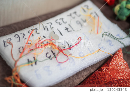 Needle and thread organizer on foam block with numbered markings. Handicraft accessory for embroidery or cross stitch planning. Diy creative project tool for sewing and crafting. Needle and thread organizer on foam block with numbered markings. Handicraft accessory for embroidery or cross stitch planning. Diy creative project tool for sewing and crafting. 139243548