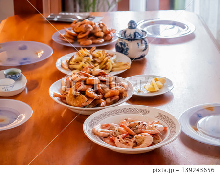 Fried shrimp served on white plates on wooden dining table. Delicious seafood dinner prepared for family gathering. Traditional meal setting with lemon and porcelain dishware. Fried shrimp served on white plates on wooden dining table. Delicious seafood dinner prepared for family gathering. Traditional meal setting with lemon and porcelain dishware. 139243656