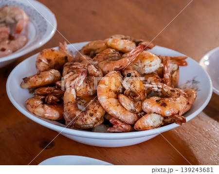 Cooked shrimp in white bowl on wooden table. Fried prawn seasoned with spice for delicious seafood dish. Gourmet meal ready to eat in restaurant. Healthy protein dinner culinary concept. 139243681