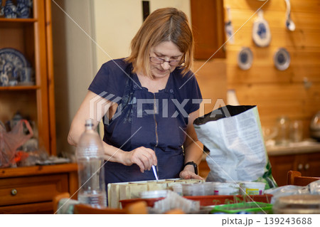 Senior woman planting seeds in pots at home. Elderly female gardener preparing seedling containers for spring season. Hobby activity, horticulture concept and sustainable home gardening. Senior woman planting seeds in pots at home. Elderly female gardener preparing seedling containers for spring season. Hobby activity, horticulture concept and sustainable home gardening. 139243688