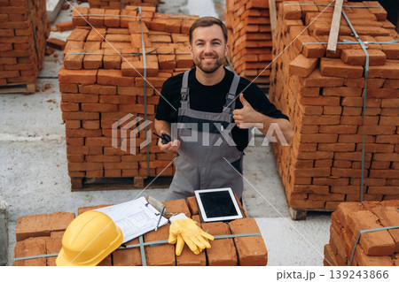 Smiling, positive facial expression. A builder is working at the construction site at daytime Smiling, positive facial expression. A builder is working at the construction site at daytime 139243866