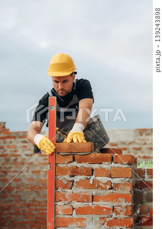 Setting the right level with special leveling tool. A builder is working at the construction site at daytime Setting the right level with special leveling tool. A builder is working at the construction site at daytime 139243898