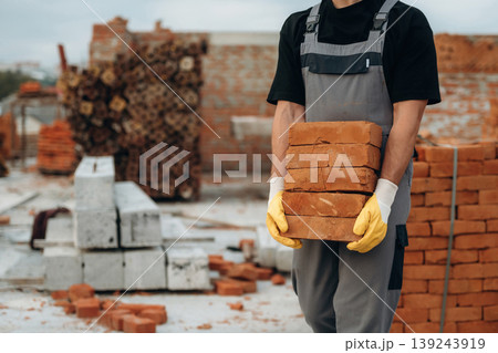 Many of the bricks are in hands. Close up view of builder that is on the construction site 139243919