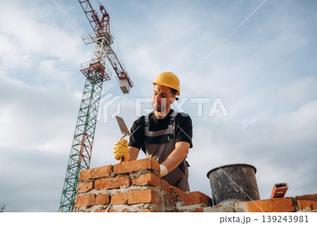 Busy, against the crane in distance. A builder is working at the construction site at daytime Busy, against the crane in distance. A builder is working at the construction site at daytime 139243981