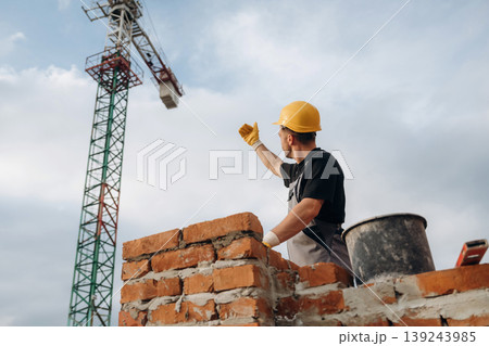 Cloudy sky behind. A builder is working at the construction site at daytime 139243985