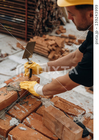 In yellow colored protective helmet. A builder is working at the construction site at daytime In yellow colored protective helmet. A builder is working at the construction site at daytime 139243999