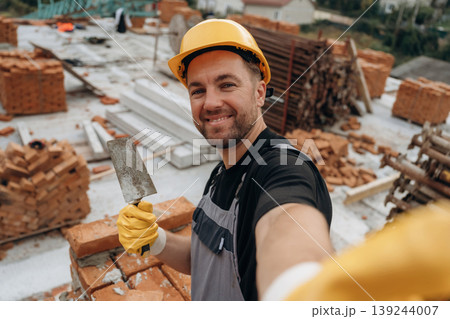 Making a selfie. A builder is working at the construction site at daytime Making a selfie. A builder is working at the construction site at daytime 139244007