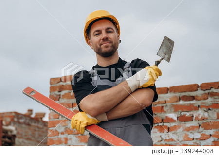In yellow colored protective helmet. A builder is working at the construction site at daytime In yellow colored protective helmet. A builder is working at the construction site at daytime 139244008