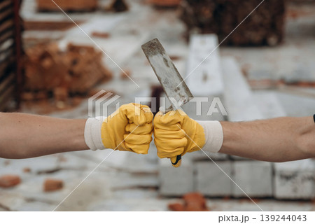 Side view of two hands of builders on construction site that are knocking the fists, conception of teamwork, unity 139244043