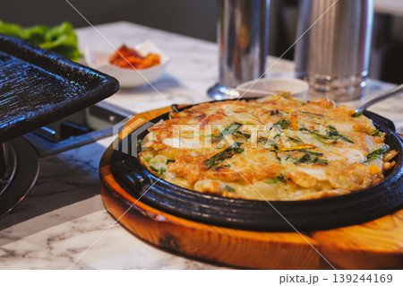 韓国料理店で提供される、鉄板の上でこんがりと焼けたクリスピーなパジョン（チヂミ） 139244169
