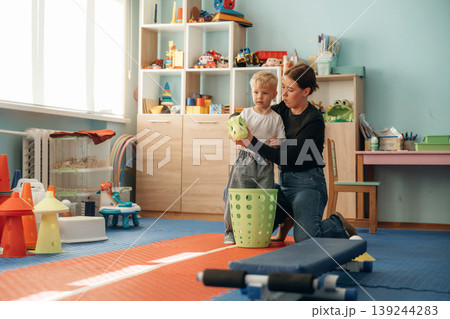 Cute dragon toy head toy, using it. Preschool child with teacher during developmental activities in a playroom 139244283