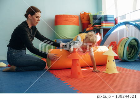 Exercises for motor skills. Preschool child with teacher during developmental activities in a playroom Exercises for motor skills. Preschool child with teacher during developmental activities in a playroom 139244321