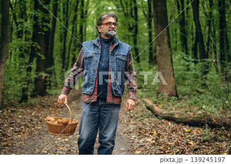 Walking, collected lot of them, in basket. Mushroom picking. Man is in the forest at daytime Walking, collected lot of them, in basket. Mushroom picking. Man is in the forest at daytime 139245197