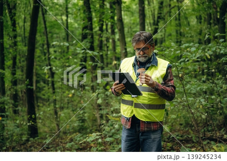 Quality control, with notepad. Senior forest ecologist is working in the woods. In the uniform Quality control, with notepad. Senior forest ecologist is working in the woods. In the uniform 139245234