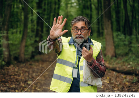 Stop hand gesture, no trespassing. Senior forest ecologist is working in the woods. In the uniform Stop hand gesture, no trespassing. Senior forest ecologist is working in the woods. In the uniform 139245245