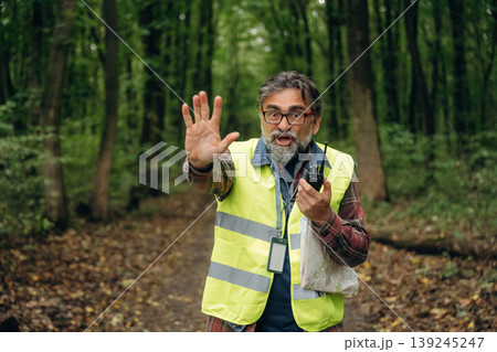 Stop hand gesture, no trespassing. Senior forest ecologist is working in the woods. In the uniform Stop hand gesture, no trespassing. Senior forest ecologist is working in the woods. In the uniform 139245247