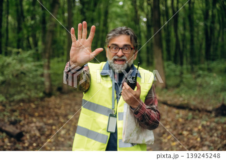 Stop hand gesture, no trespassing. Senior forest ecologist is working in the woods. In the uniform Stop hand gesture, no trespassing. Senior forest ecologist is working in the woods. In the uniform 139245248