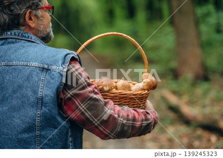 In jacket, with basket. Mushroom picking. Man is in the forest at daytime 139245323