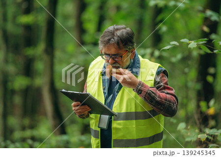 Safe to eat or not, checking, with notepad. Senior forest ecologist is working in the woods. In the uniform Safe to eat or not, checking, with notepad. Senior forest ecologist is working in the woods. In the uniform 139245345