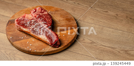Raw t-bone steak with coarse salt on wooden board, top view copy space Raw t-bone steak with coarse salt on wooden board, top view copy space 139245449