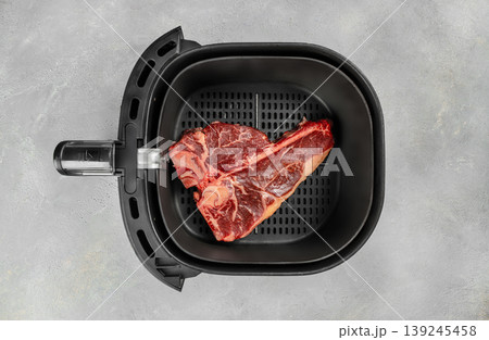 Raw porterhouse steak in air fryer basket on light concrete background, top view Raw porterhouse steak in air fryer basket on light concrete background, top view 139245458