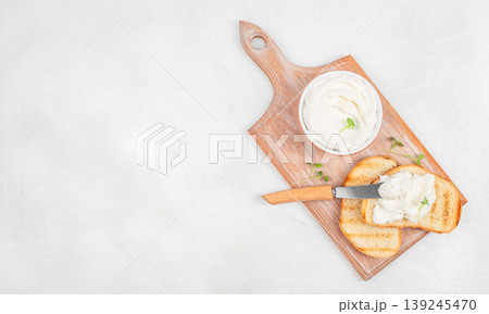Cream cheese spread on toast with knife on wooden board, top view with copy space Cream cheese spread on toast with knife on wooden board, top view with copy space 139245470