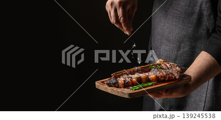 Chef seasoning sliced steak with salt falling in motion on dark background premium food concept. copy space 139245538