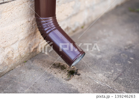 Homeowner checks drain for deterioration. Evaluating moss and rust on drainage outlet Homeowner checks drain for deterioration. Evaluating moss and rust on drainage outlet 139246263