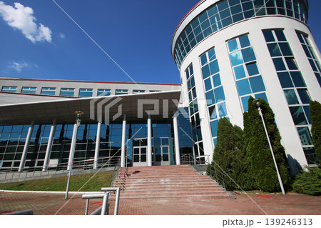 Sophisticated corporate edifice with reflective surfaces and structured landscaping 139246313