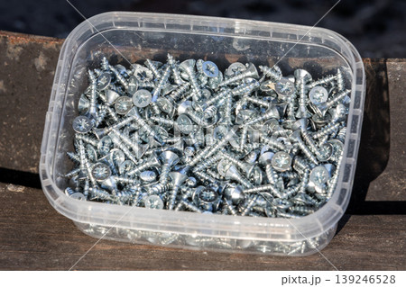 A plastic box filled with shiny galvanized screws 139246528
