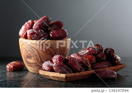 Dates fruit in wooden dish on a black table. Dates fruit in wooden dish on a black table. 139247094