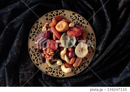 Dried tropical fruits and nuts in a golden bowl. Dried tropical fruits and nuts in a golden bowl. 139247110