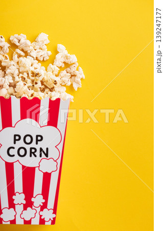 Popcorn in white striped paper box and spill on Yellow Background Popcorn in white striped paper box and spill on Yellow Background 139247177