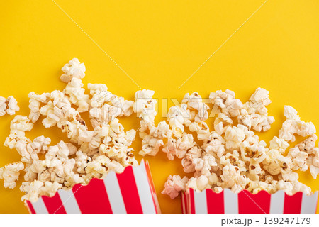 Popcorn in white striped paper boxes and spill on Yellow Background Popcorn in white striped paper boxes and spill on Yellow Background 139247179