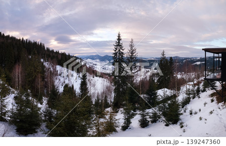 Evening winter snow-covered mountain ridge, Ukraine, Carpathians. Porch of an unrecognizable holiday cabin on the right. Evening winter snow-covered mountain ridge, Ukraine, Carpathians. Porch of an unrecognizable holiday cabin on the right. 139247360