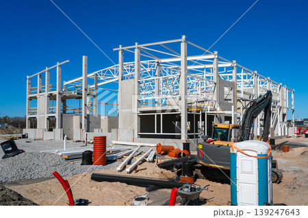 Industrial building construction site with steel frame, excavator and materials under blue sky 139247643