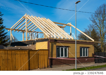 Wooden roof frame under construction on residential house renovation project in suburban area Wooden roof frame under construction on residential house renovation project in suburban area 139247646