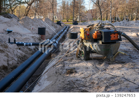 Underground insulated utility pipeline installation with dewatering equipment in construction trench 139247653