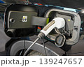 Electric vehicle charging port close-up with plugged charger connector on modern black EV car 139247657
