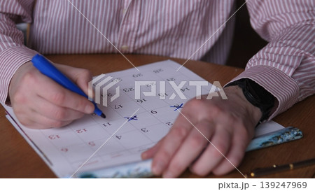 Hands Marking Paper With Blue Pen, Closeup Of Checklist Grid Showing Crosses And Corrections, Adult At Desk Wearing Striped Shirt, Wristwatch Visible, Concentrated Gesture Indicating Hands Marking Paper With Blue Pen, Closeup Of Checklist Grid Showing Crosses And Corrections, Adult At Desk Wearing Striped Shirt, Wristwatch Visible, Concentrated Gesture Indicating 139247969