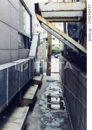 Urban Alleyway with Concrete Walls and Puddles 139248437