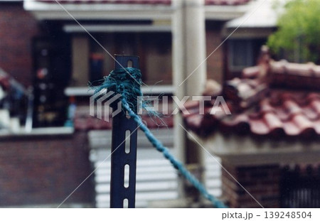 Blue Rope Tied to Metal Post with House Background Blue Rope Tied to Metal Post with House Background 139248504