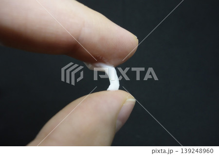 Fingers Holding Small White Object Close-Up 139248960
